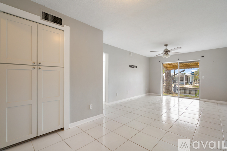A spacious room with a ceiling fan and sliding glass doors leading to a balcony.