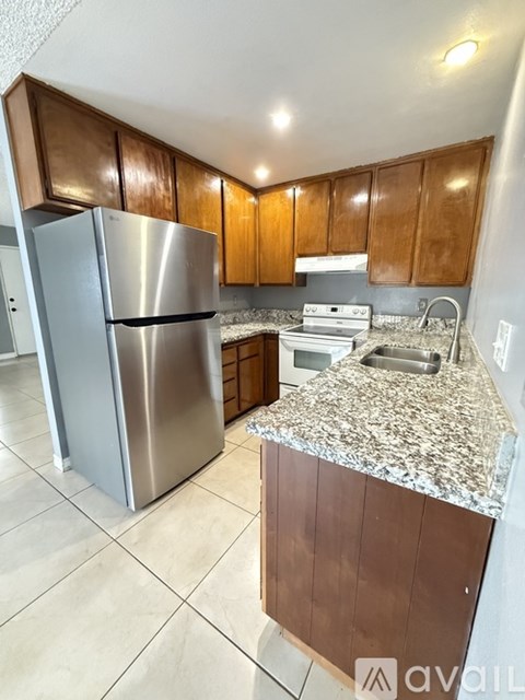 A kitchen with a stainless steel refrigerator and wooden cabinets.