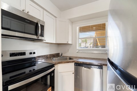 A kitchen with a stainless steel dishwasher and black appliances.