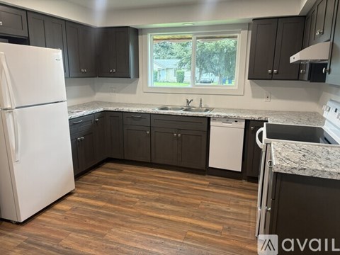 A kitchen with a white refrigerator and dark wood cabinets.