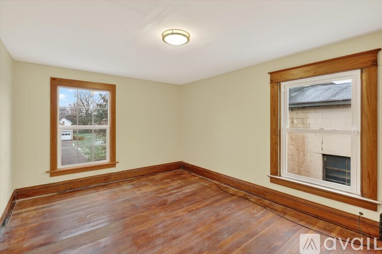A room with wooden floors and two windows.