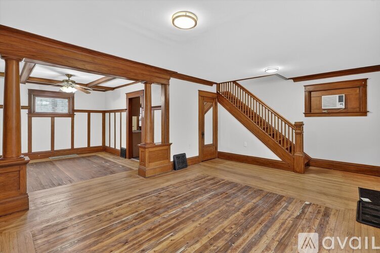 A spacious room with wooden floors and a staircase.
