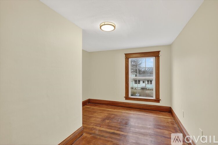 A room with wooden floors and a window showing a view of a building outside.