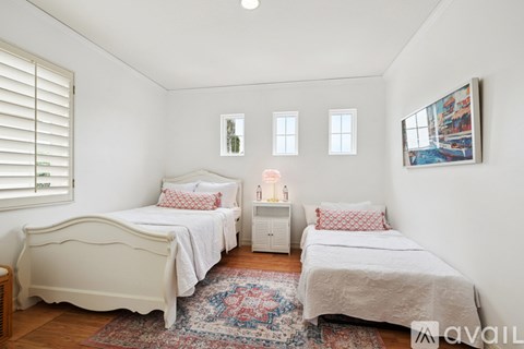 A bedroom with two beds and a rug on the floor.