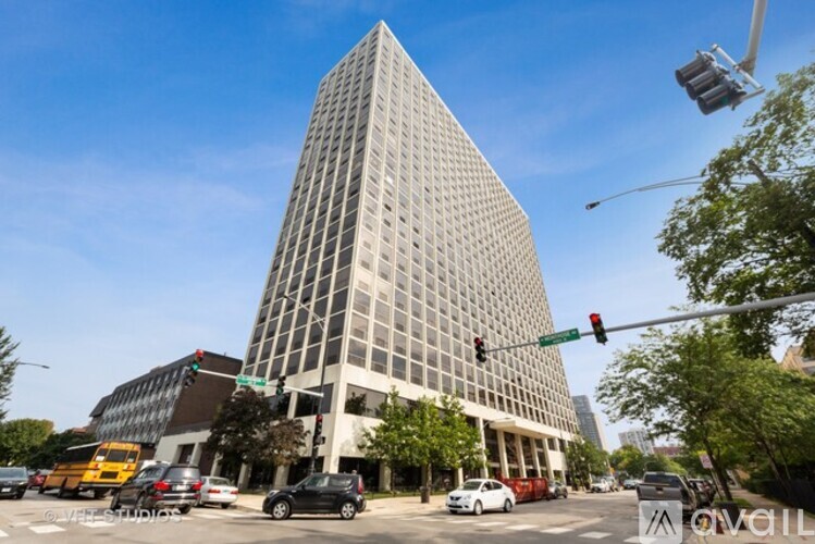 A tall building with a grid-like facade stands in front of a busy street.