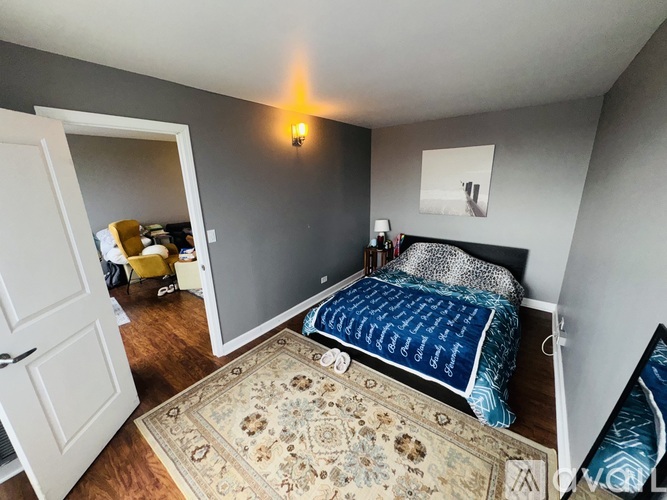A bedroom with a bed, a rug, and a yellow chair.