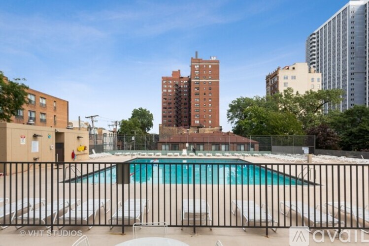 A pool surrounded by a fence with buildings in the background.