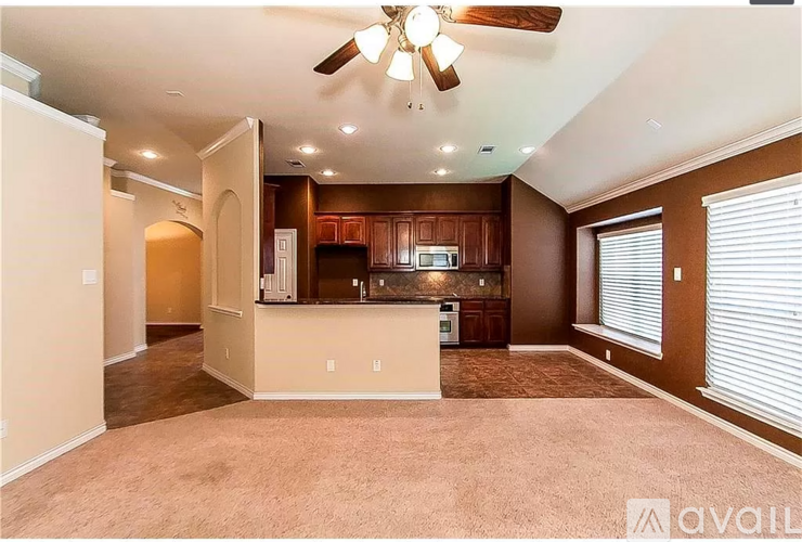A spacious living room with a kitchen area in the background.