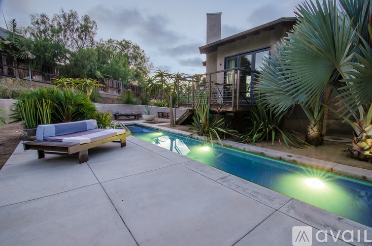 A pool with a bench and a house in the background.