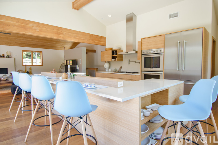 A kitchen with a white counter and blue chairs.
