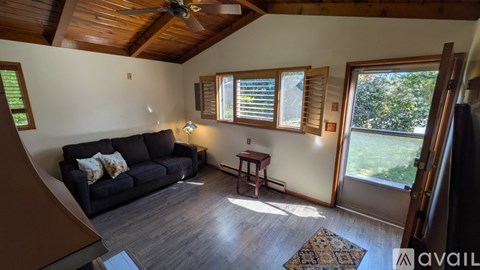 A living room with a black couch and a ceiling fan.