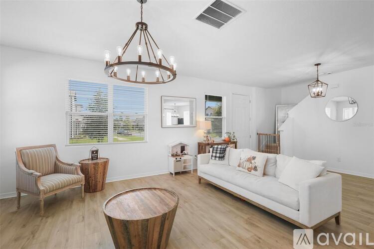 A living room with a white couch, a wooden chair, and a wooden coffee table.