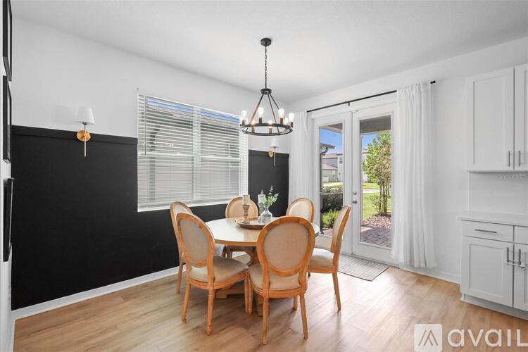 A dining room with a table set for four and a chandelier hanging from the ceiling.