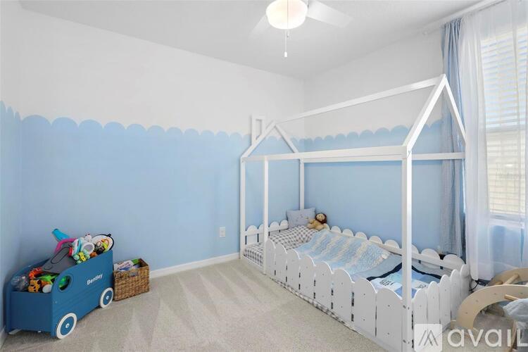 A child's bedroom with a white canopy bed and a blue toy chest.