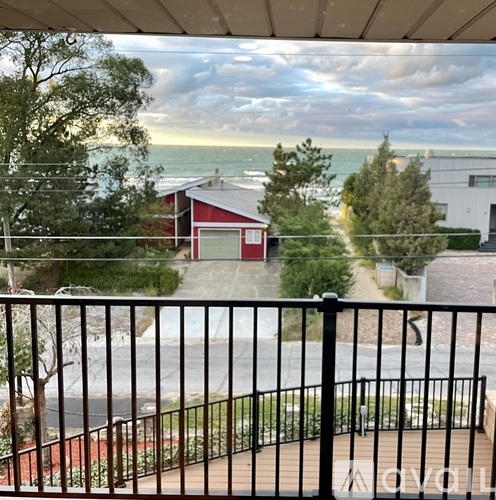 A red building is situated on a hillside with a view of the ocean.