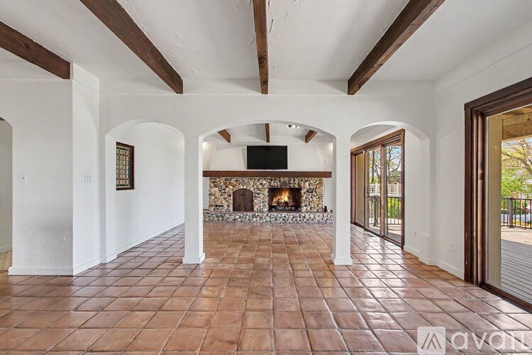 A spacious living room with a fireplace and a television mounted on the wall.