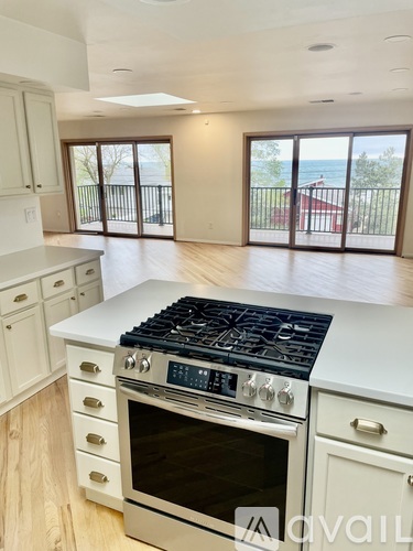 A kitchen with a stove top oven and a view of the backyard.