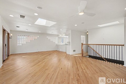 A spacious room with wooden floors and a ceiling fan.