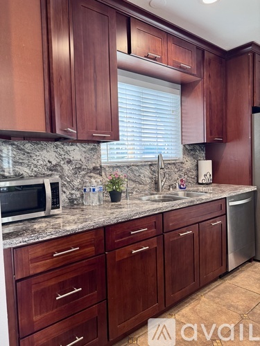 A kitchen with brown cabinets and a marble countertop.