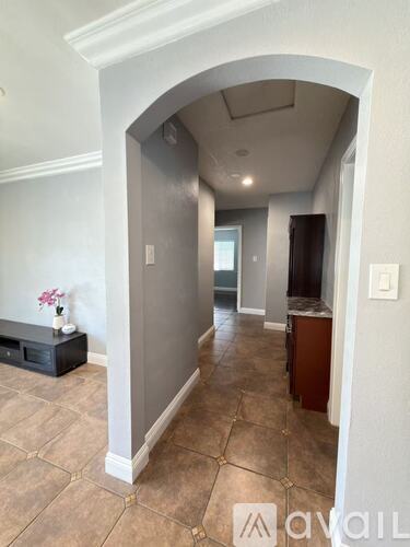 A hallway with a bench and a vase of flowers.