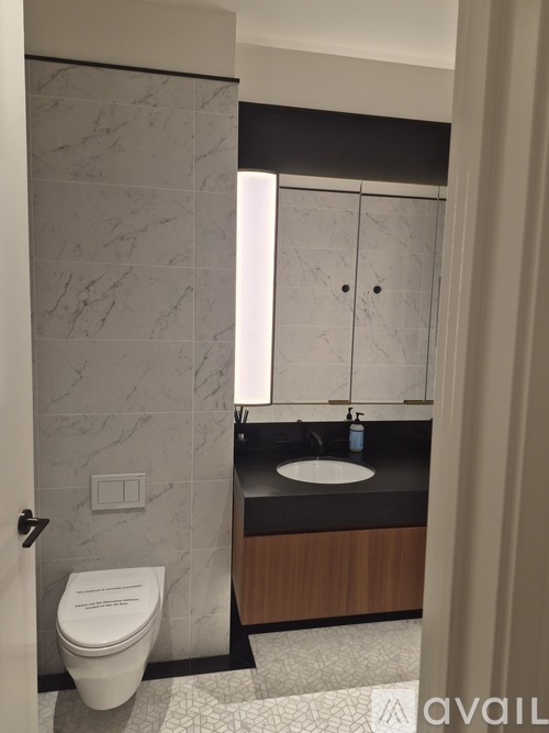 A bathroom with a toilet, sink, and a marble wall.
