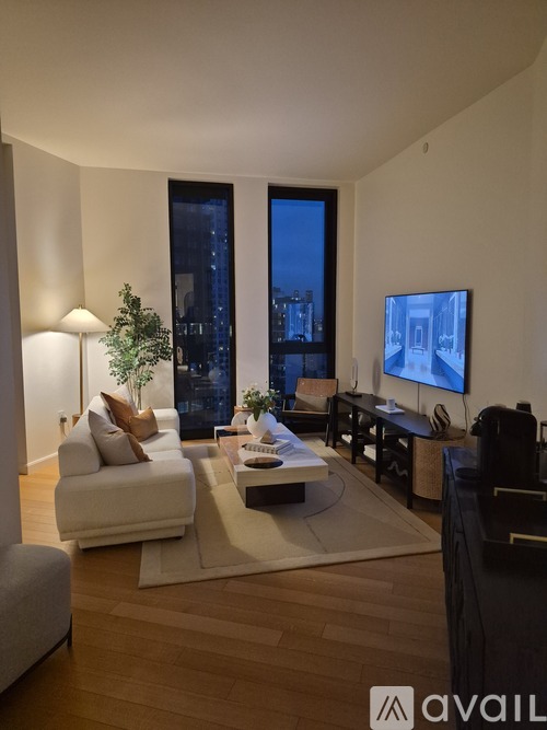 A modern living room with a large window overlooking the city at night.
