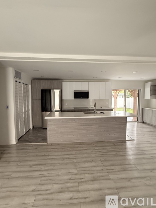 A modern kitchen with a central island and a television mounted above it.