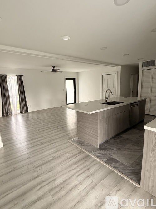 A spacious room with a wooden floor and a ceiling fan.