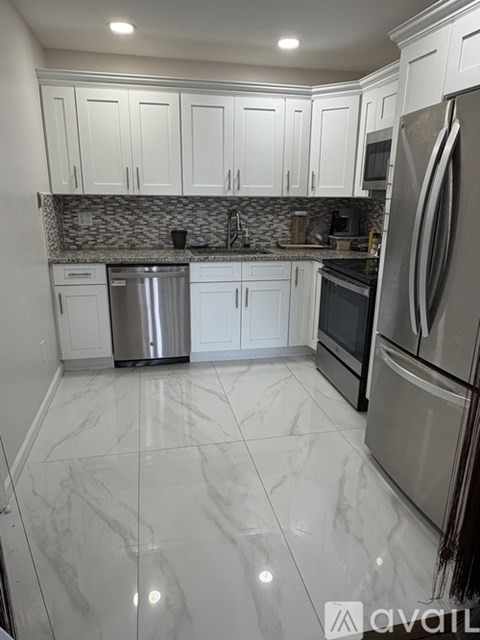 A kitchen with white cabinets and a marble floor.