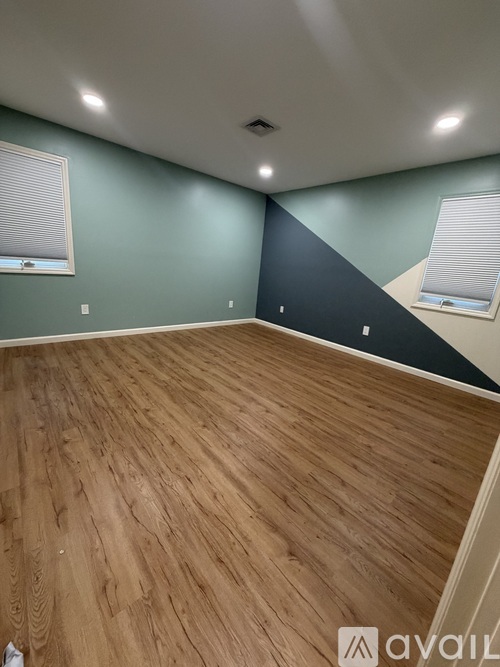A room with wooden flooring and a window with blinds.