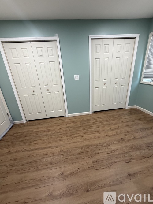 A room with two white doors and wooden flooring.