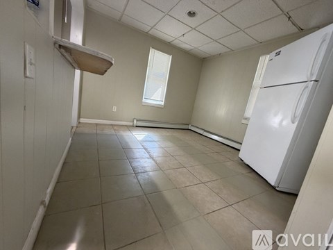 A kitchen with a white refrigerator and a window with blinds.