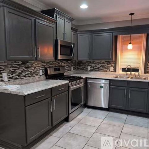 A kitchen with dark cabinets and a stone backsplash.