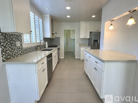 A kitchen with white cabinets and a black and white tiled backsplash.