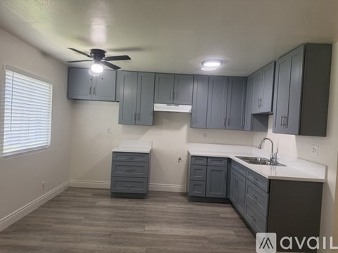 A kitchen with a fan on the ceiling and cabinets above the counter.