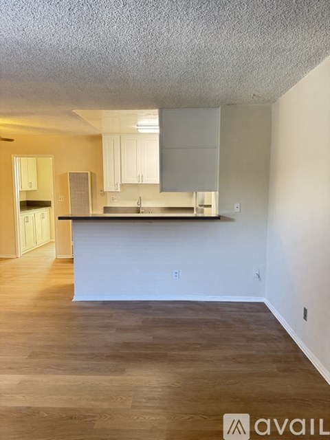 A kitchen with white cabinets and a wooden floor.