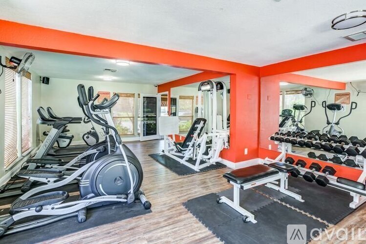 A gym with a variety of equipment including treadmills, weights, and a bench.