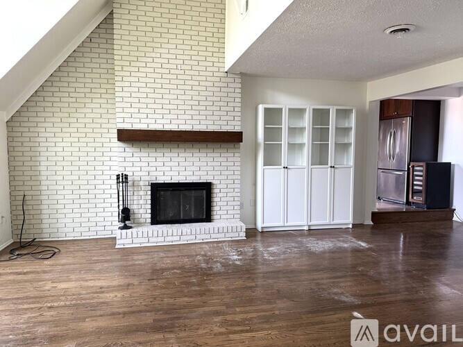 A living room with a fireplace and a white brick wall.