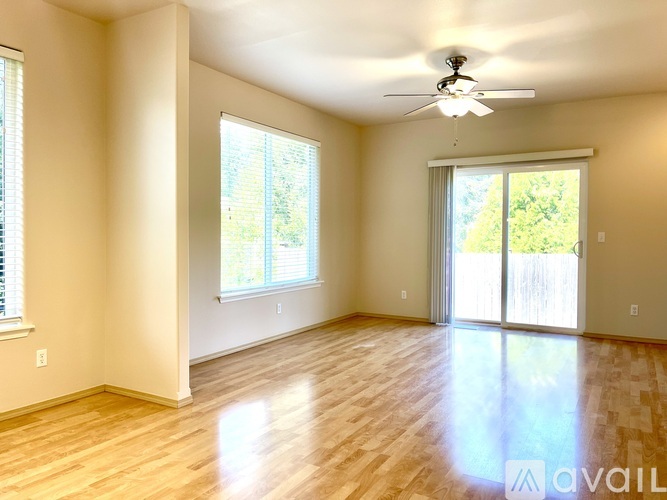 A spacious room with wooden floors and a ceiling fan.