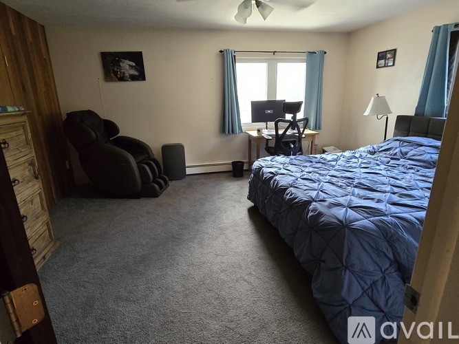 A bedroom with a bed, chair, and desk.