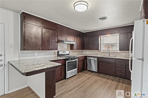 A kitchen with brown cabinets and a white fridge.