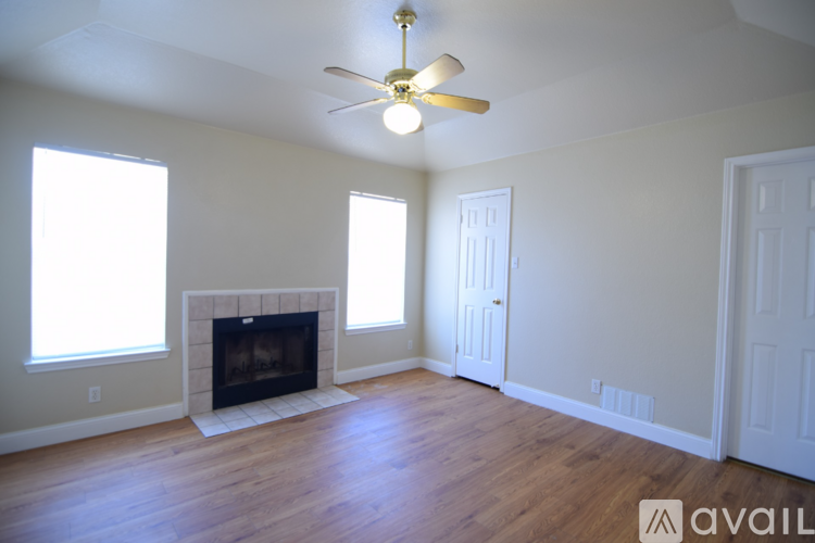 A living room with a fireplace and a ceiling fan.