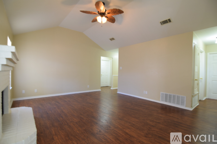 A spacious room with a ceiling fan and hardwood floors.