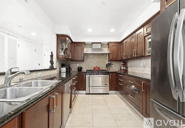 A kitchen with brown cabinets and a black refrigerator.
