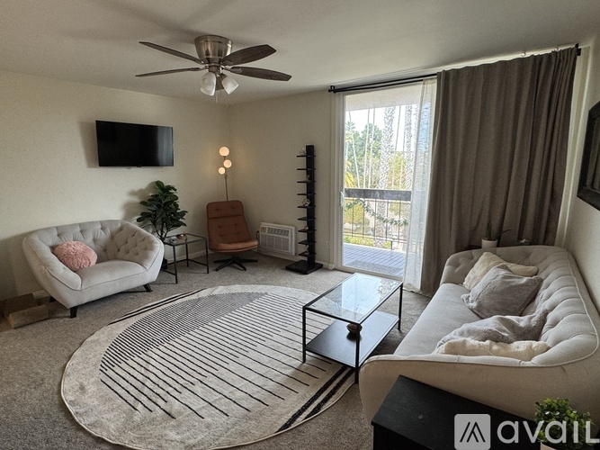 A living room with a white couch, a glass coffee table, and a television mounted on the wall.