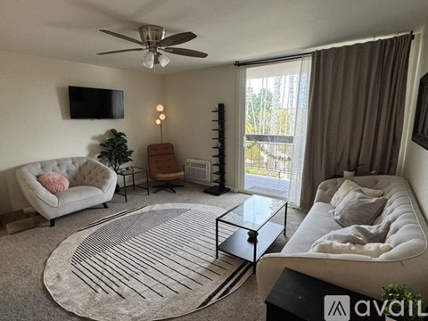 A living room with a white couch, a glass coffee table, and a television mounted on the wall.