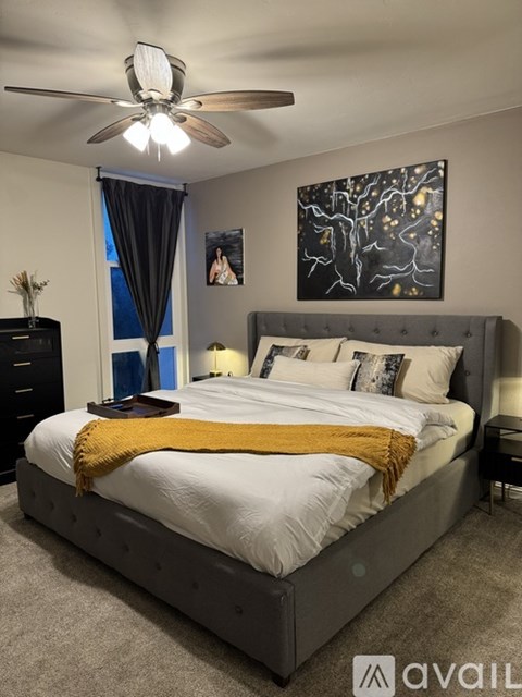A bedroom with a large bed and a ceiling fan.