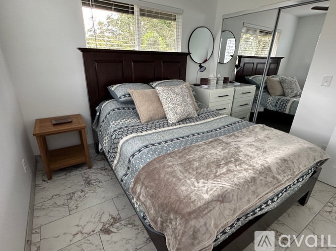A bedroom with a large bed and a mirror on the wall.
