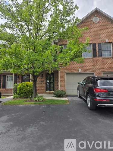 A black SUV is parked in front of a brick house.