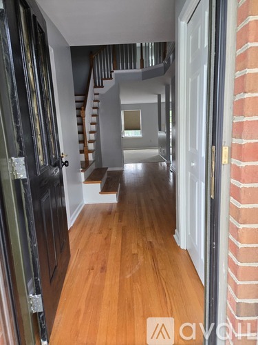 A hallway with a wooden floor and a brick wall.